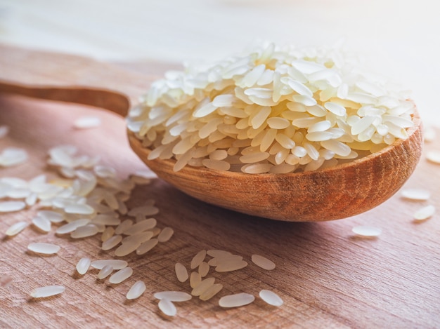 Riz étuvé et cuillère en bois sur une table en bois.