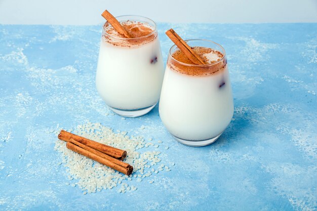 Riz frais traditionnel mexicain ou espagnol fait maison Horchata dans un verre sur fond bleu. Boisson fraîche fraîche ou cocktail à base de riz, de vanille et de cannelle ou d'amande.