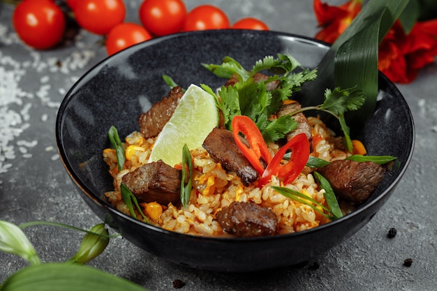 Riz frit au boeuf et légumes sur un fond texturé gris