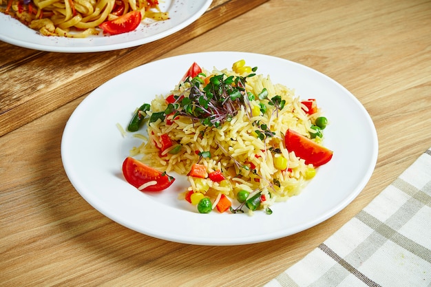 Riz frit au wok avec différents légumes sur une plaque blanche. Végétarien, nourriture saine. Mise à plat. Fermer