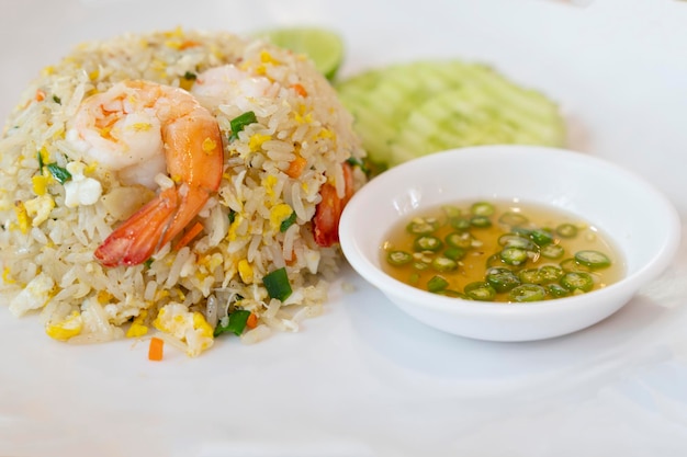 Riz frit aux crevettes sur une assiette blanche avec piment de sauce de poisson dans une tasse