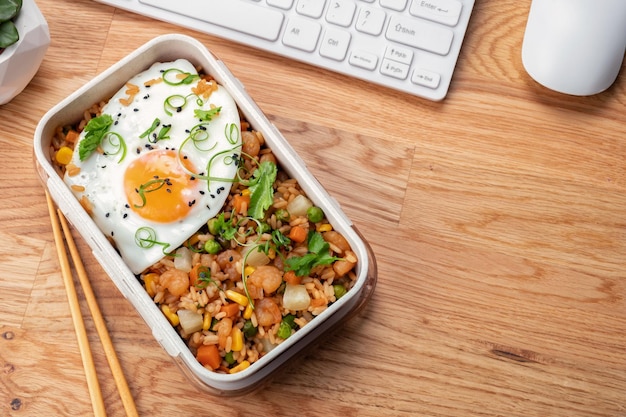 Riz frit aux crevettes avec légumes et œuf dans une boîte à lunch