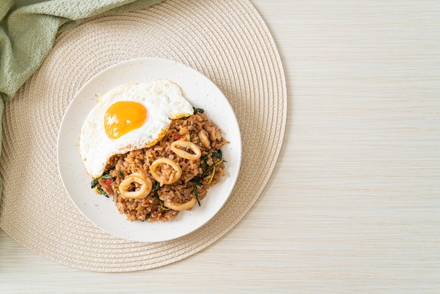 Riz frit avec calamars et œuf frit garni de basilic dans un style de cuisine asiatique de style thaï