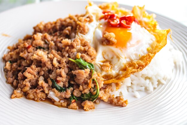 Riz garni de porc sauté et de basilic servi avec un œuf au plat.