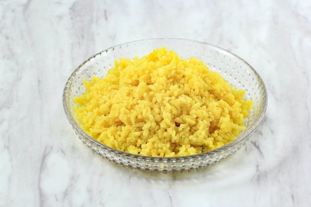 Riz jaune cuit dans une assiette une portion de Nasi Kuning cuit dans une assiette en céramique, servi sur une table en marbre