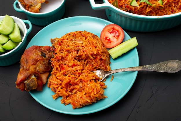 Riz Jollof avec de la viande de poulet sur une assiette Riz aux tomates oignons épices Cuisine nigériane nationale traditionnelle Fond sombre