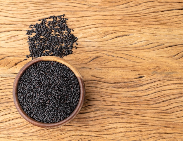 Riz noir cru dans un bol sur une table en bois avec espace de copie