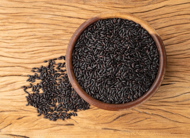 Riz noir cru dans un bol sur une table en bois