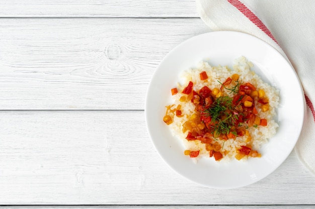 Riz préparé avec des légumes sur une table en bois blanche