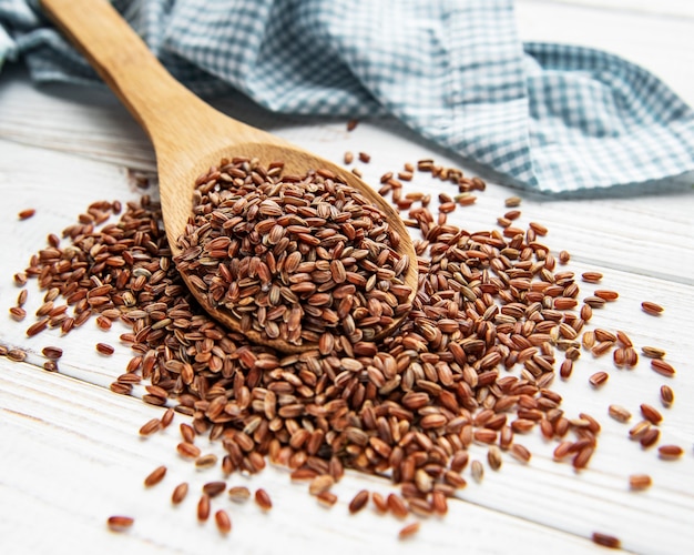 Riz rouge cru sur un fond en bois blanc