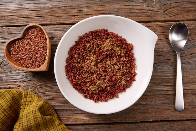 Riz sauvage rouge dans une assiette blanche sur du bois