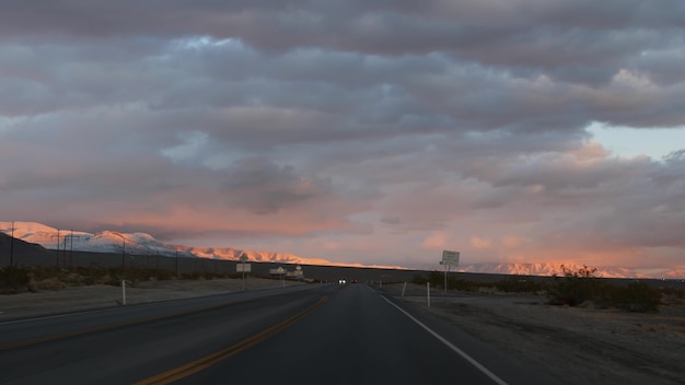 Road trip, conduite automobile de Death Valley à Las Vegas, Nevada USA. Faire de l'auto-stop en Amérique. Voyage sur l'autoroute, atmosphère dramatique, montagne au coucher du soleil et désert de Mojave. Vue depuis la voiture.