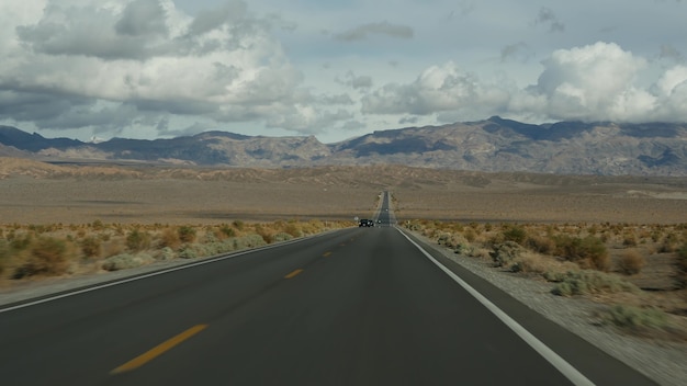 Road trip à Death Valley, conduite automobile en Californie, USA. Faire de l'auto-stop en Amérique. Autoroute, montagnes et désert sec, désert de climat aride. POV passager de la voiture. Voyage au Nevada.