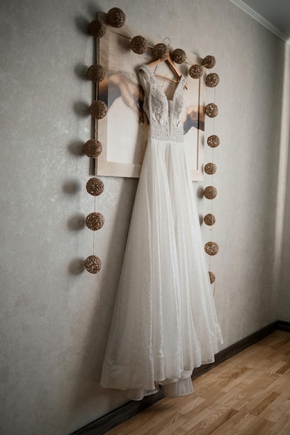 Robe longue de mariée en dentelle ivoire accrochée à un cintre en bois