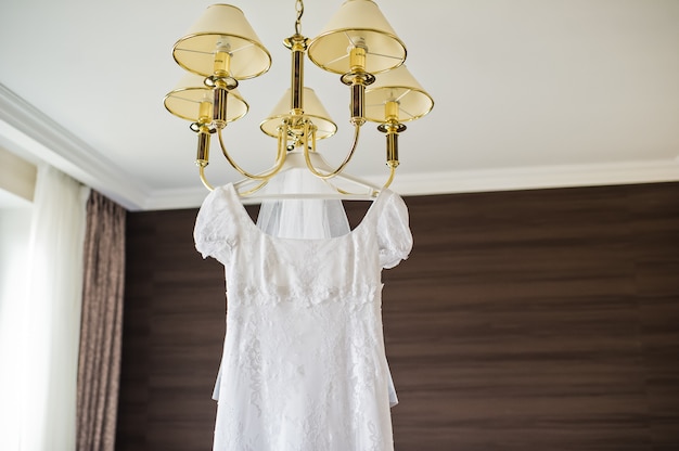 Robe de mariée élégante suspendue au lustre à l'intérieur de l'hôtel