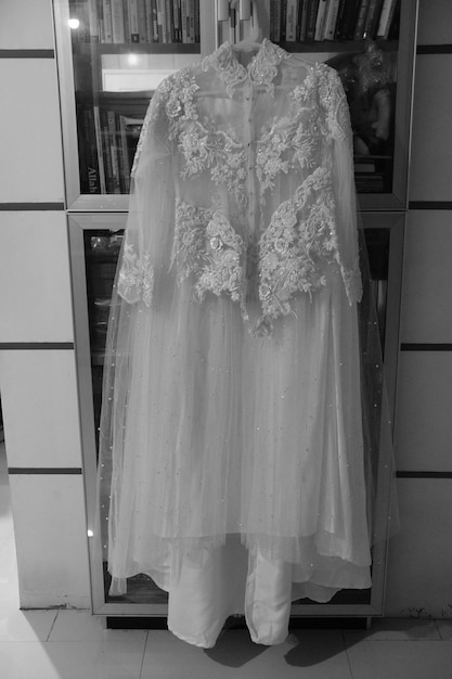 Une robe de mariée est accrochée sur une étagère dans un magasin.