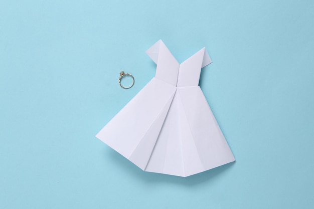 Robe de mariée origami et alliance sur fond bleu