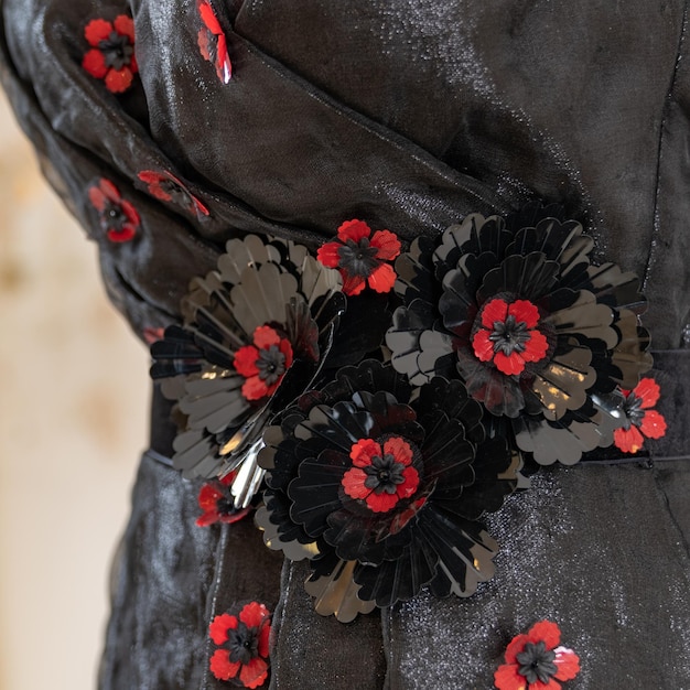 Une robe noire avec des fleurs rouges et noires dessus.