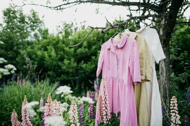 Robes de couleur naturelle accrochée à un arbre dans le jardin avec des fleurs de lupin