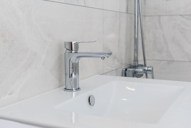 Robinet avec un lavabo dans la salle de bain avec des carreaux gris.