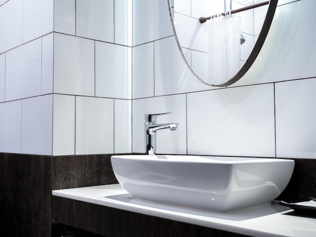 Robinet moderne en acier inoxydable sur un lavabo en céramique blanche dans la salle de bain avec miroir Lavabo en céramique de forme rectangle propre sur une décoration de comptoir en marbre avec des carreaux de mur à motif de rouille de style loft