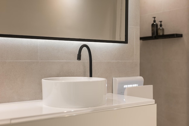 Robinet noir et lavabo rond blanc sur colonne Salle de bain moderne de style minimaliste