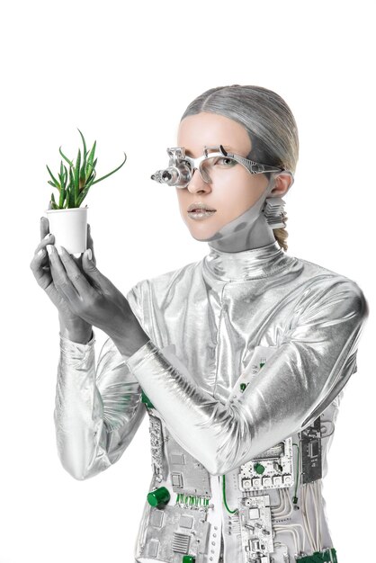 un robot argenté tenant une plante en pot et regardant une caméra isolée sur le concept de technologie du futur blanc