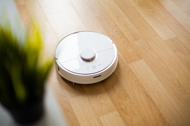 Le robot aspirateur fonctionne sur du parquet dans un bureau