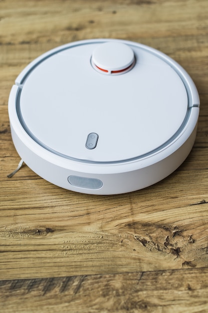 Robot aspirateur sur plancher en bois. Vue de côté. Concept de maison intelligente. Nettoyage automatique.