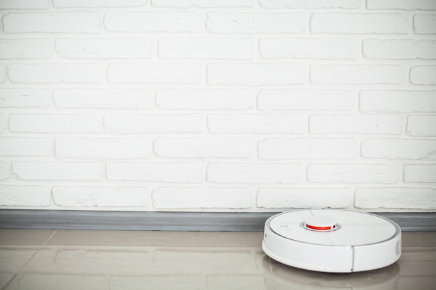 Le robot aspirateur Smart House fonctionne sur du parquet dans un salon