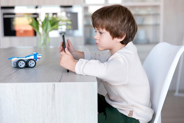 Un robot en briques est contrôlé par un programmeur d'enfants d'âge préscolaire qui utilise une tablette comme contrôleur distant.