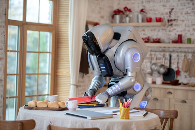 Robot debout tout en regardant des livres et des cahiers de la table