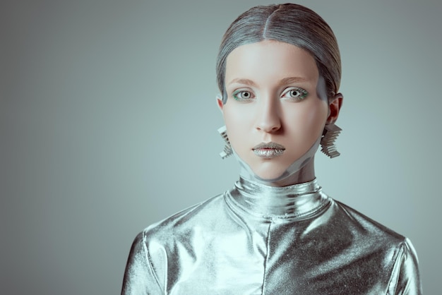 robot féminin futuriste argenté regardant la caméra isolé sur le concept de technologie du futur gris