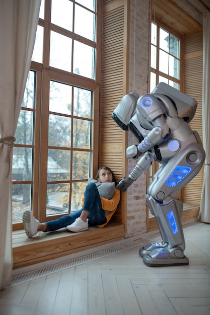 Robot parlant à la fille assise à la fenêtre