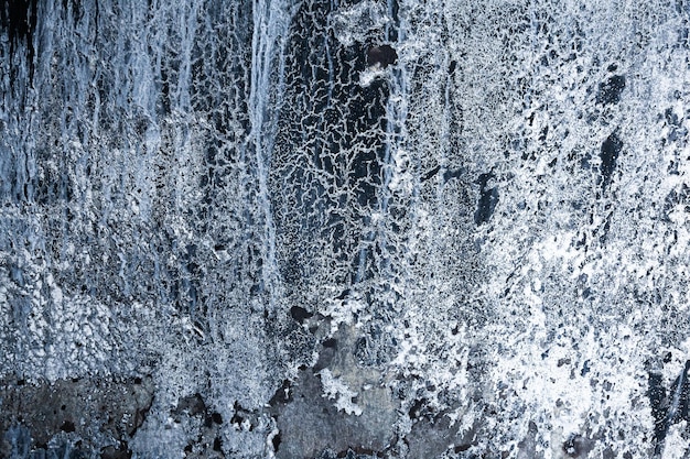 Roche noire verticale avec de la glace et de la neige Abstraction d'une roche glacée avec de la neige