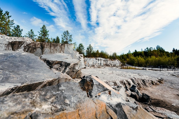 La roche a sculpté une surface non traitée de marbre blanc et gris dans un environnement naturel. La texture de la carrière de marbre bleu.