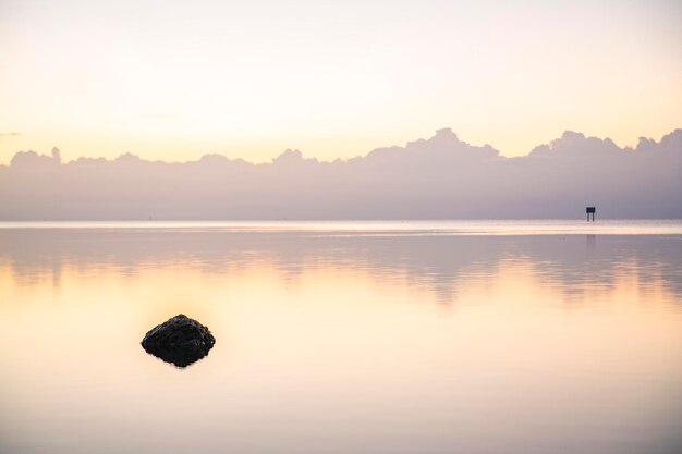 Un rocher dans l'eau avec des montagnes en arrière-plan