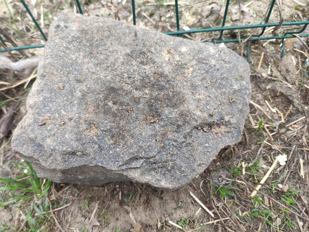 Un rocher est posé sur un grillage et le sol est recouvert de terre
