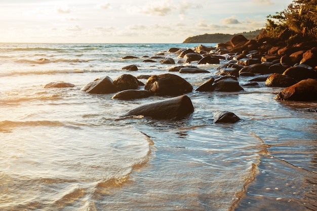 Rocher sur la plage avec coucher de soleil.