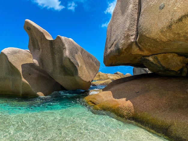 des rochers de granit sur une plage des Seychelles avec un ciel bleu et une eau claire