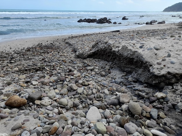 Les rochers sur la plage sont empilés et l'eau est de couleur bleue.