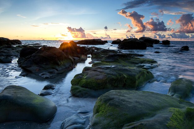 Photo des rochers sur le rivage contre le ciel au coucher du soleil