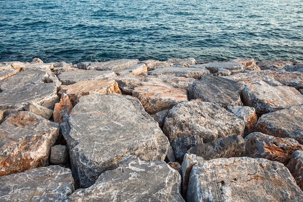 Les rochers sont de gros renforts artificiels, empilés au bord de la mer devant l'eau.