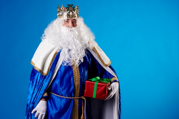 Le roi magicien avec un cadeau sur fond bleu