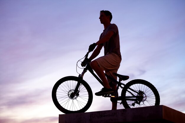 Roi de la ville Silhouette tirée d'un homme faisant du vélo au crépuscule