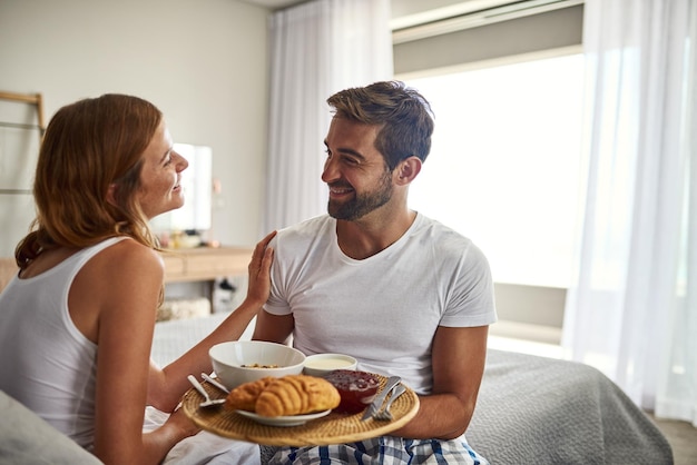La romance est le petit-déjeuner au lit Photo d'un jeune couple heureux prenant son petit-déjeuner au lit ensemble à la maison
