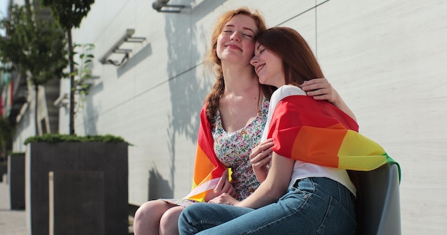 Romance et portrait d'un couple de lesbiennes profitant d'un sourire d'étreinte et se tenant l'un l'autre avec un drapeau Pride Event concept d'amitié