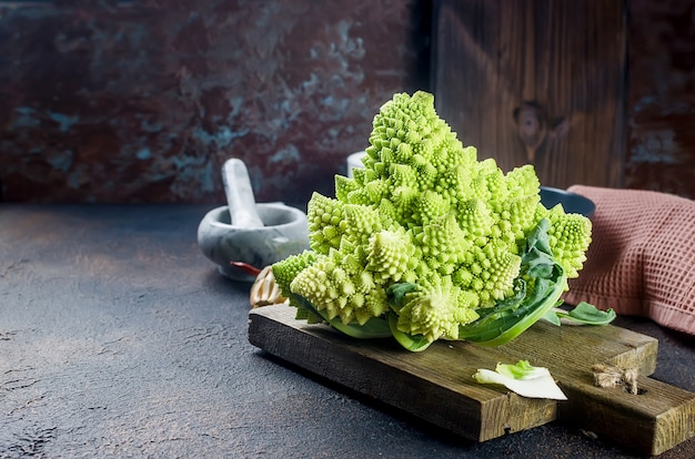 Romanesco Vert Frais, Chou Biologique Cru Prêt Pour La Cuisson Sur Une Planche à Découper Sur Fond De Bois Foncé