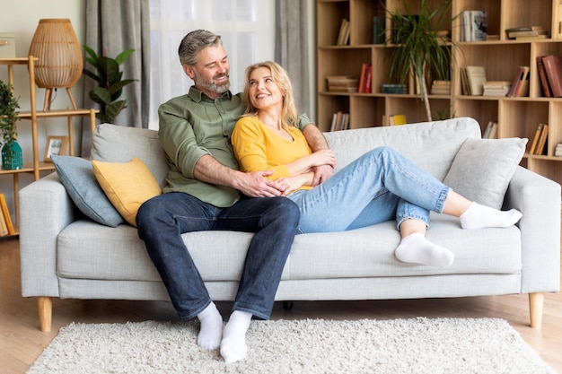 Romantique heureux couple d'âge moyen relaxant sur un canapé à la maison