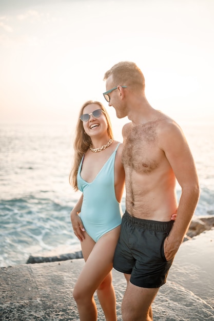 Romantique jeune couple amoureux marchant ensemble au coucher du soleil le long de la plage méditerranéenne. Vacances d'été dans un pays chaud. Heureux couple marié en vacances en Turquie. Mise au point sélective